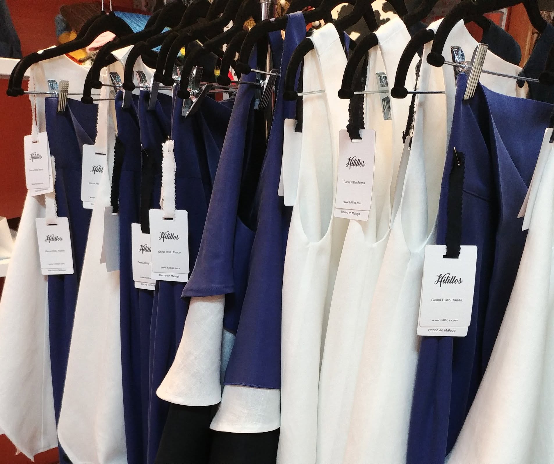 Prendas blancas y azules diseñadas por Hilillos expuestas en la tienda